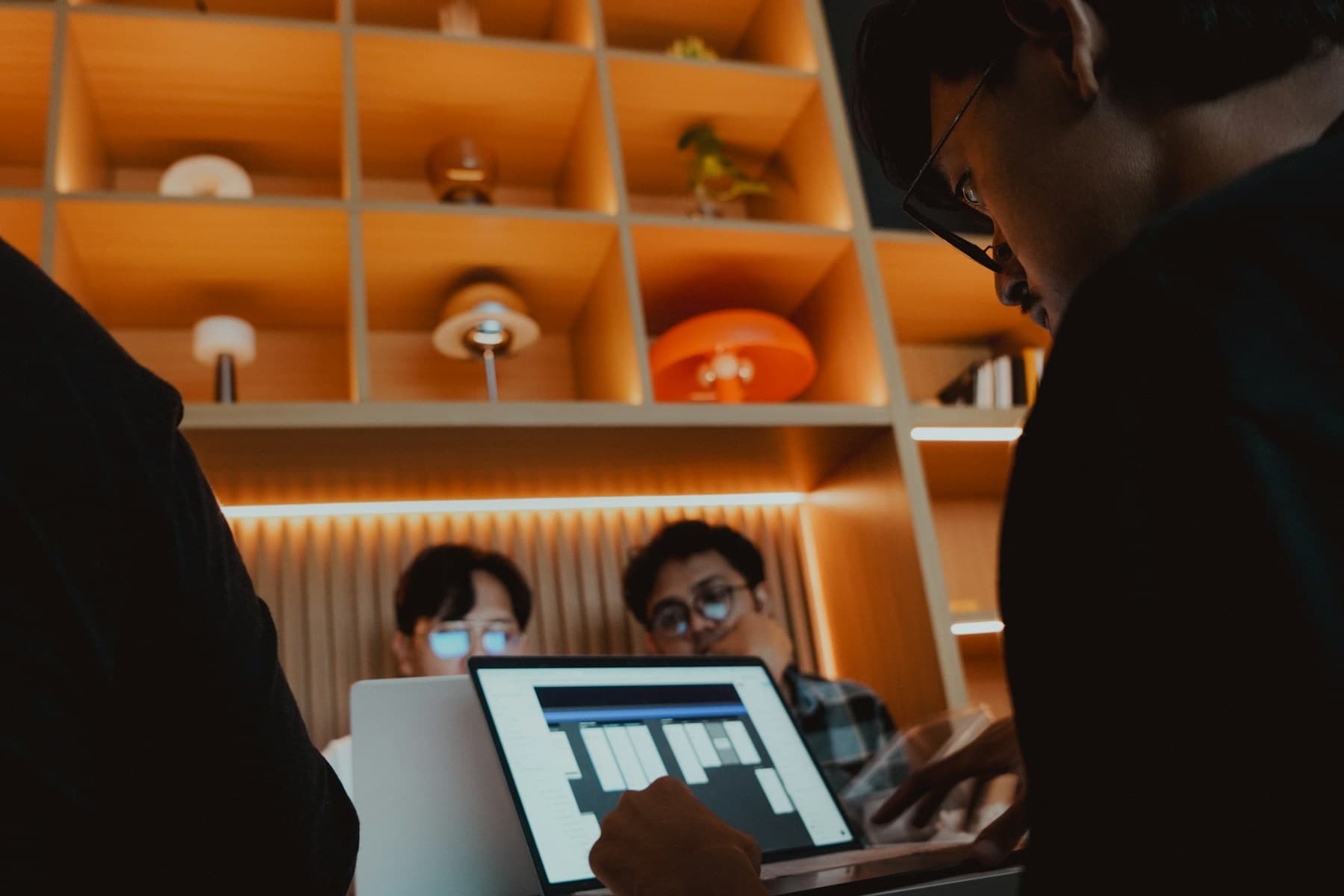 Designers collaborating around a laptop in a warm studio